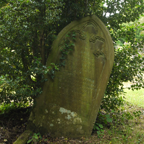 The headstone on Leah Partridge's grave shelters from the elements under a holly bush.